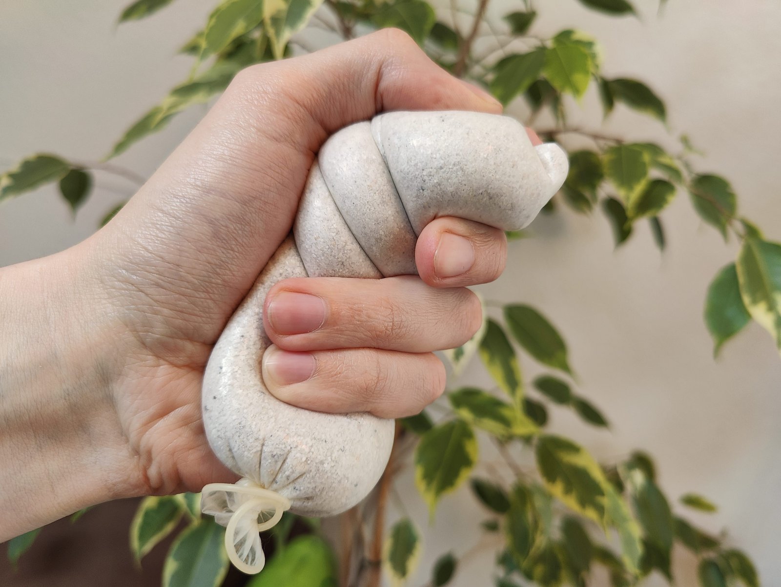 Просроченный презерватив, наполненный песком, в руке человека, использующего его в качестве мяча для снятия напряжения